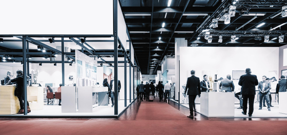 Photo montrant des professionnels évoluant entre des stands d’exposition au salon, illustrant le design moderne et la modularité d’un stand professionnel optimisé pour attirer les visiteurs et valoriser l’image d’entreprise.