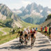 Peloton de cyclistes gravissant une route de haute montagne, entouré de spectateurs, avec les reliefs alpins sous une lumière estivale.