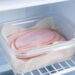 Tranches de jambon blanc séparées par du papier cuisson dans une boîte hermétique placée au congélateur.