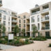 Immeubles résidentiels neufs dans une grande ville française, avec façades contemporaines, espace paysager et panneaux immobiliers vierges.