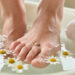 Gros plan non graphique d’un pied de femme présentant un œil-de-perdrix douloureux entre les orteils, accompagné de soins naturels apaisants.