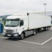 Tracteur routier électrique blanc avec semi-remorque stationné sur une plateforme logistique près de Villefranche-sur-Saône, avec des bornes de recharge pour poids lourds visibles.